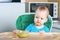 Llittle baby does not want to eat first complementary food. Disgruntled child at highchair