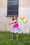 Llittle girl in rainbow coloured dress and bare feet swinging two balloons