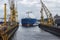 LNG carrier arriving to a ship repair yard assisted by multiple tugboats. Floating dock is submerged to allow the vessel in.