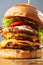 Loaded cheeseburgers three triple, stacked patties stacked high with layers of cheese, lettuce, and tomato. Tall
