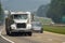 A Loaded Flatbed Eighteen-Wheeler Leads Traffic On A Foggy Day