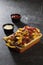 Loaded fries or wild fries topping with tomato ketchup, melted cheese and mayonnaise isolated on dark grey background side view of