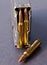 A loaded rifle magazine with .223 caliber bullets with a single hollow point bullet next to it