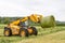 Loader tractor moving a round bale from field