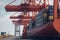 Loading a container ship at cargo berth of the seaport using port cranes. Containers are stacked and secured on board