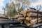 Loading heavy industrial truck trailer with big timber pine, spruce, cedar logs by crane grab loader tractor machine. Pile