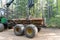 Loading logs on a truck trailer using a tractor loader with a grab crane. Transportation of coniferous logs to the sawmill.