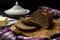 Loaf of bread on wooden cutting board, butter and purple tea towel. Dark background