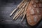 Loaf of crusty brown bread golden wheat rye ears on wood board