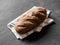 Loaf dark buckwheat bread on white textile napkin black table background. Fresh delicious homemade healthy bake. Bakery