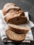 Loaf dark buckwheat bread on white textile napkin black table background. Fresh delicious homemade healthy bake. Bakery