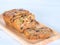 A loaf of fruit cake in wooden plate with defocused of dried fruit, spices and honey