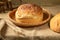 A loaf of homemade white bread in a basket on a burlap tablecloth