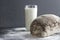 Loaf or rye bread an glass of milk on flour,dark table,grey wall.Rustic mood.Quick snack