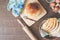 Loaf and sliced homemade bread with sesame, eggs and kitchen tools on wood