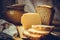 Loaf of sourdough sliced bread on wood cutting board, chunk of cheese, clay dishware, knife, rural kitchen interior