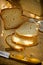 Loaf of sourdough whole wheat bread cut into slices, golden crust, chunk of cheese, linen towel, wood kitchen table