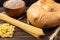 Loaf, wheat and pasta on dark wooden background