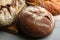 Loaves of delicious fresh bread on grey wooden table, closeup