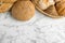 Loaves of different breads on white marble background, flat lay. Space