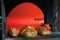 Loaves of fresh baked bread in front of oven with fire inside, advertising photo