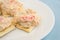 Lobster dip on saltine crackers on blue table cloth