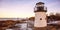 Lobster point lighthouse along the rocky coast of Maine at sunset on the Marginal Way path in Ogunquit during winter