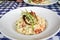 Lobster risotto in a white bowl topped with a half a grilled lobster tail