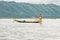 Local Burmese fisherman posing for photos with his net, balancing and steering boat with one foot.