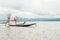 Local Burmese fisherman posing for photos with his net, balancing and steering boat with one foot.