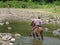 Local cowboy rides a horse through river, Nicaragua