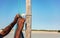 Local Malagasy man securing sail rope to a wooden pole of his ship, detail to hands only