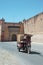 Local man riding an improvised motorcycle carriage passing nearby the walls and an old gate of El Badi Palace