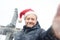 Local man in a Santa Claus hat takes selfie on street near the Manhattan Bridge in New York City on Christmas Eve during a