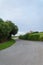 Local road with house, meadows and trees, a cloudy afternoon at sunset