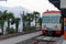 Local smiling train in Lugano, Switzerland, with palm trees and mountain silhouettes