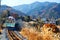 A local train travels on Seibu Chichibu Railway thru the idyllic countryside with fiery autumn trees on the mountainside & golden