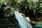 local villagers standing on the top of a small jungle rainforest waterfall at the remote tropical paradise south pacific island