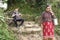 Local woman and trekker resting on mountain path.