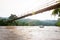 A local wooden boat passing the suspension wooden bridge at dusk