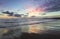 Location place Agia Marina Beach, island Crete, Greece. Sea coast spangled by rocks, the sunrise is reflecting on the wet sand.