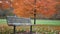 Locked down shot of a park bench in autumn near park