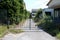 Locked rusted metal doors protecting entrance to abandoned factory with completely overgrown driveway surrounded with deserted bui