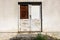 Locked white wooden doors with cracked dilapidated paint and rusted padlock on old grey wall with concrete steps in front