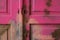 Locked wooden old door, pink, ruined, peeling color.