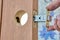 Locksmith installs doorknob with latch on wooden interior door.