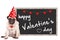 Loevel cute pug puppy dog wearing party hat with hearts, sitting next to blackboard sign with text happy valentine`s day, on white