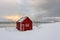 Lofoten Islands in Norway and their beautiful winter scenery at sunset. Idyllic landscape with red house on snow covered beach. To