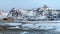 Lofoten islands, Norway. Typical houses of the fishermen rorbu, on the snowy beach, mountains in background.