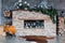 Loft style. Interior with brick fireplace, candles, greenery, modern chair skin of cows, grey wall, firewoods, modern design.